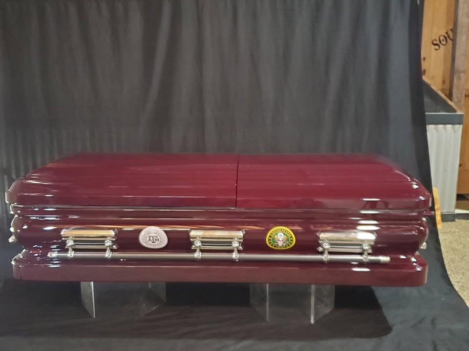 Deep burgundy adult casket with chrome bar handles, a Texas A&M medallion and a US Army seal