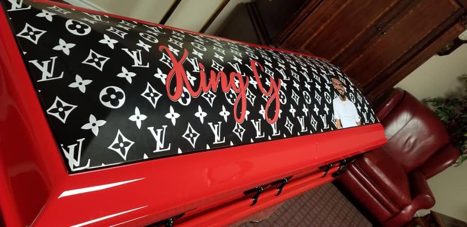 Bright red casket topped with a black and white designer monogram panel and Kingly in red script
