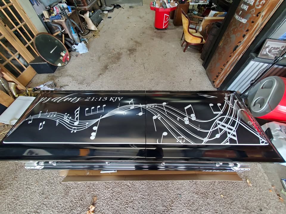 Gloss black casket flowing with white musical notes and staff lines beside Psalms 21:13 KJV