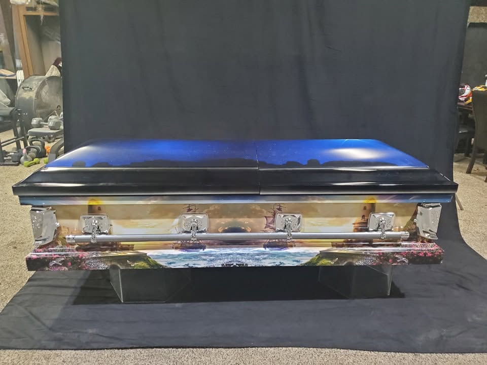 Night sky blue lid over a wraparound lighthouse and crashing surf seascape on this adult casket