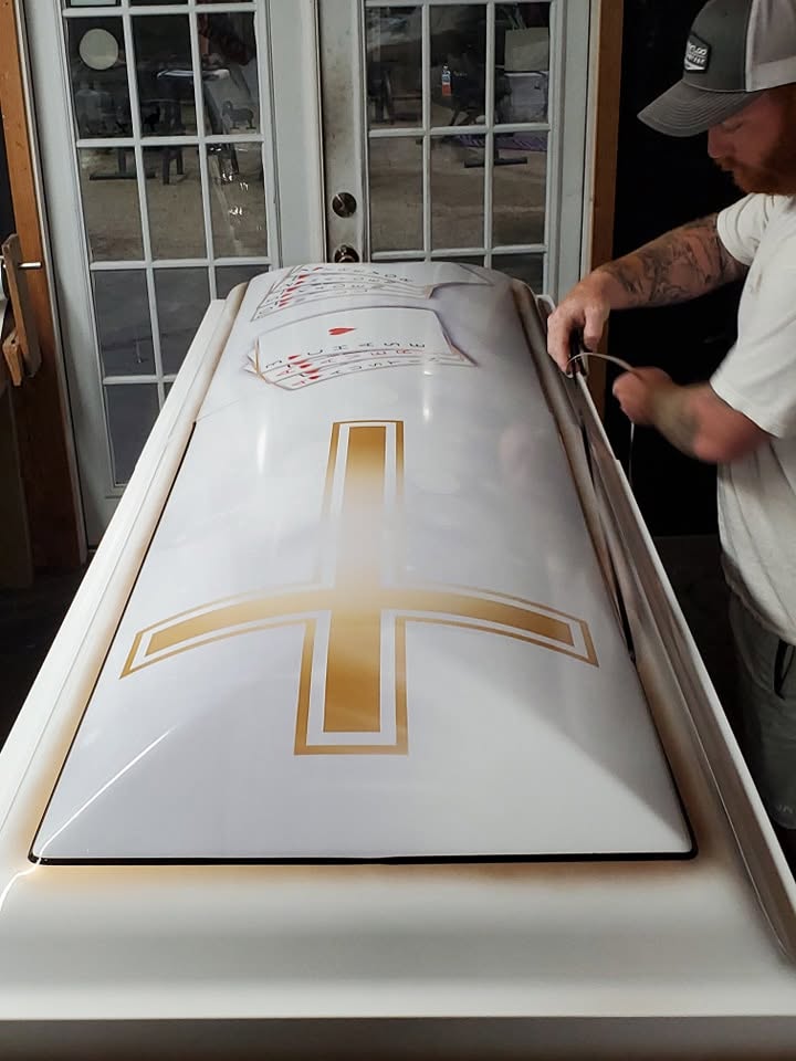 Gloss white casket with a large gold cross and playing card artwork and fitted trim