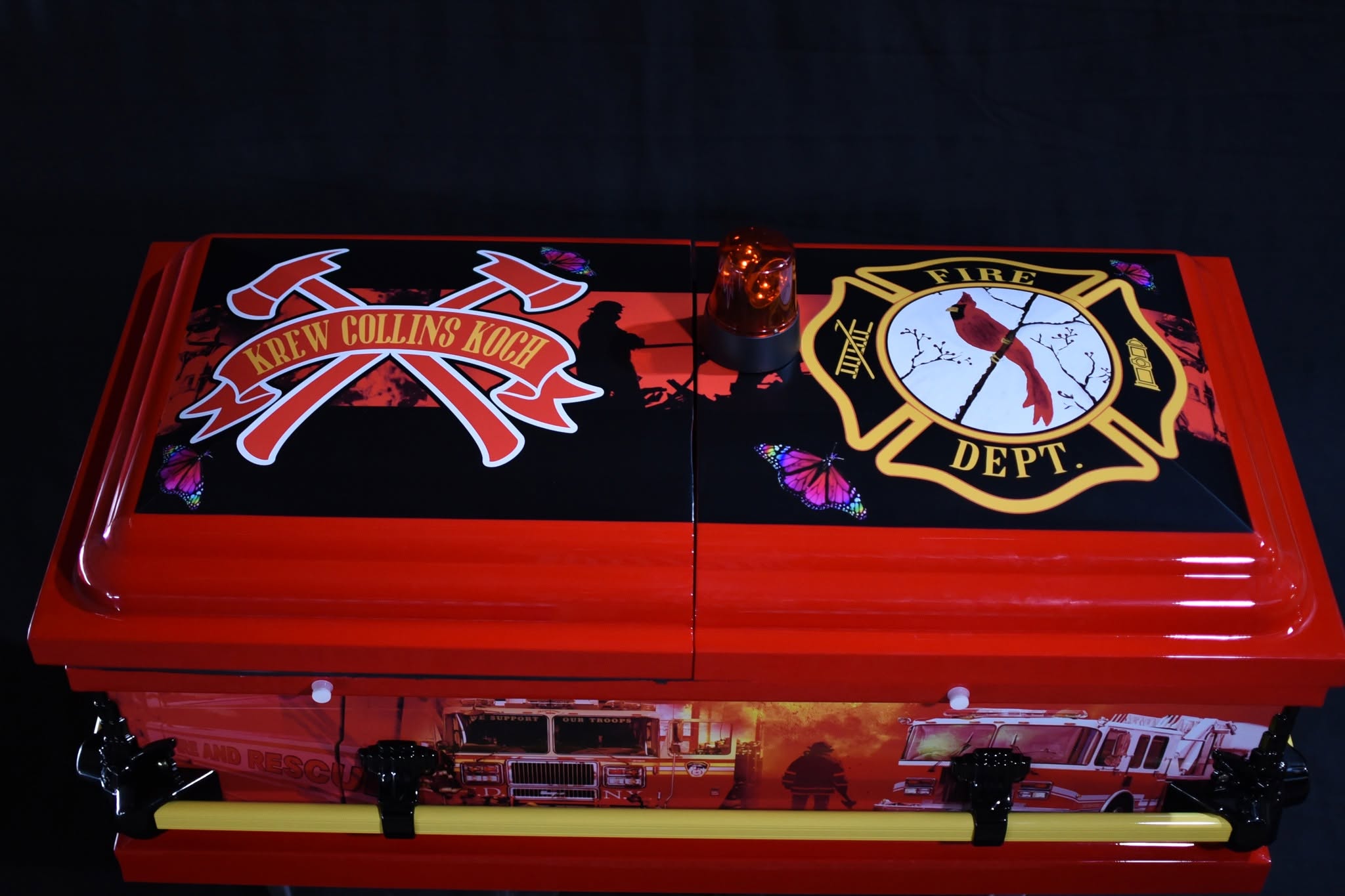 Fire engine red casket with a Fire Dept Maltese cross, crossed axes and Krew Collins Koch banner
