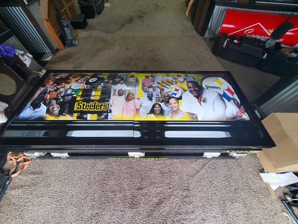 Black casket topped with a Pittsburgh Steelers logo collage and printed family photographs