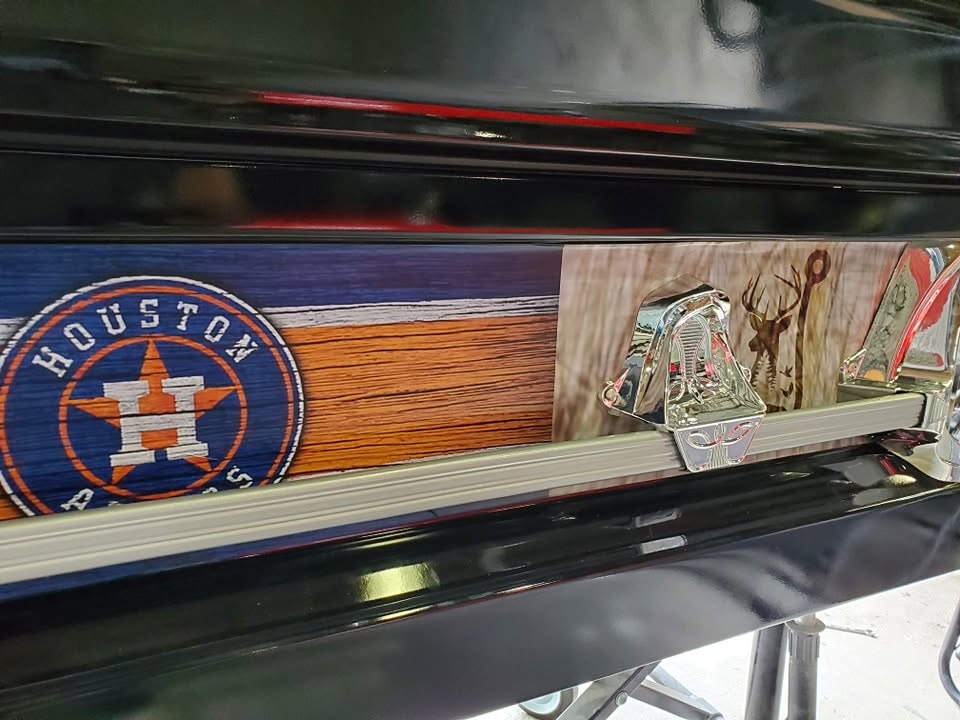 Houston Astros logo on barn wood beside a deer silhouette panel along a black casket side rail