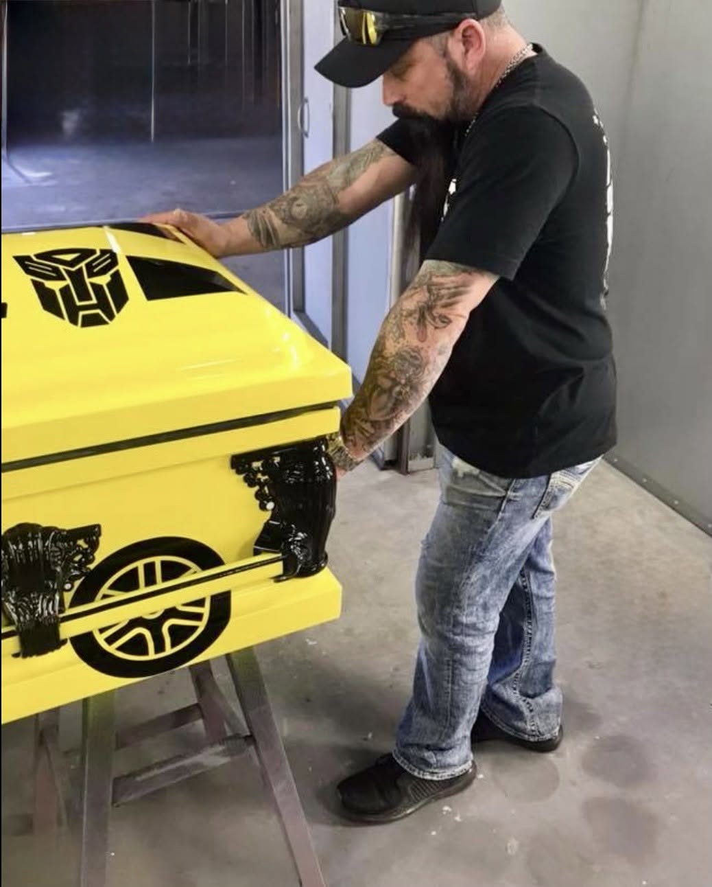 Bumblebee yellow casket with a black Autobot emblem and wrapped wheel details