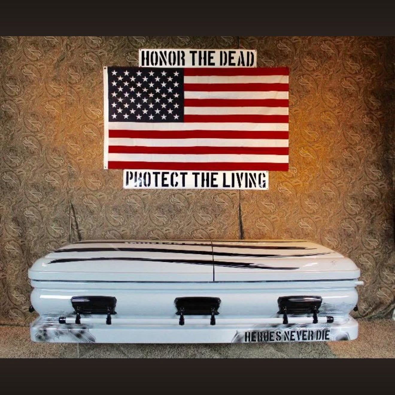 White casket lettered HEROES NEVER DIE below an American flag and Honor the Dead tribute banners