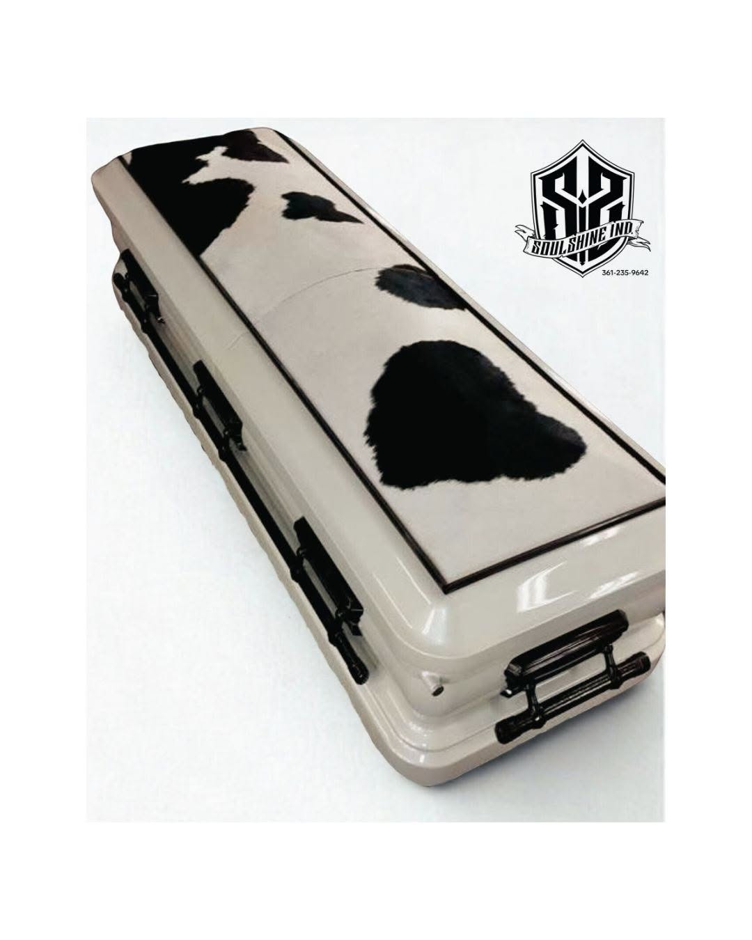 Cream casket topped with a black and white cowhide print panel and slim black bar handles