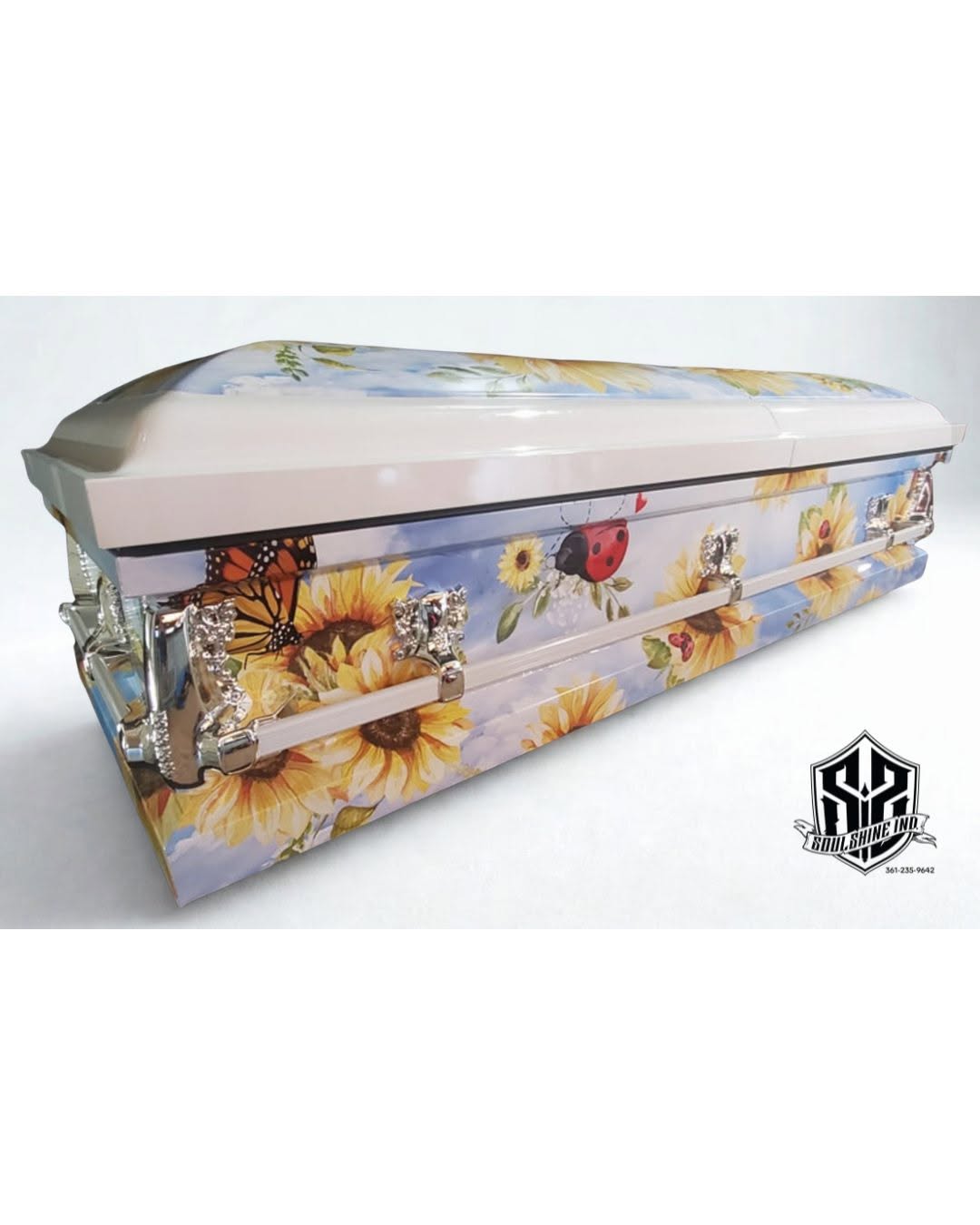 Sunflowers, a monarch butterfly and a ladybug on the wrap across a cream and sky blue casket