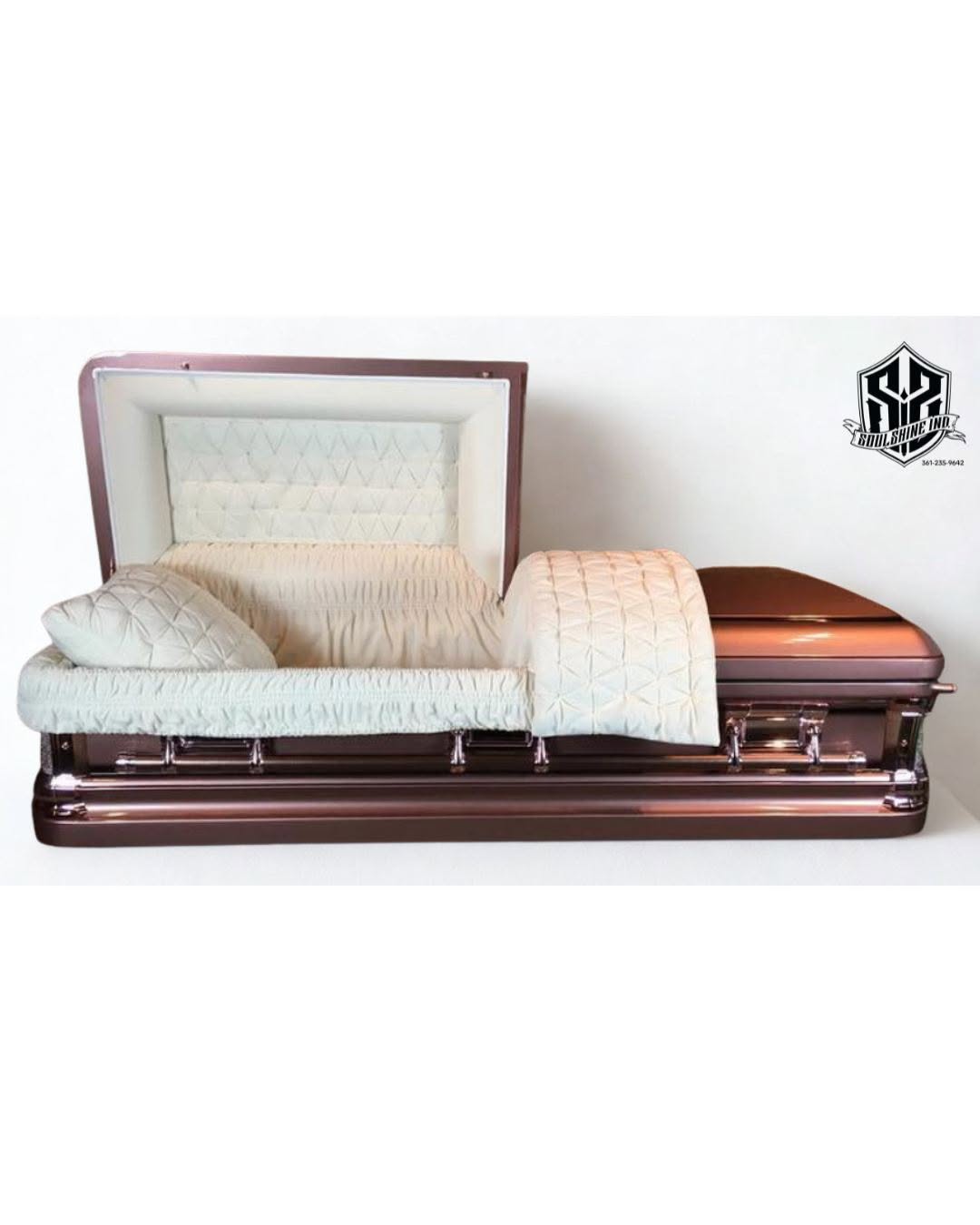 Rose copper metallic casket open to reveal a quilted ivory crepe interior and chrome handles