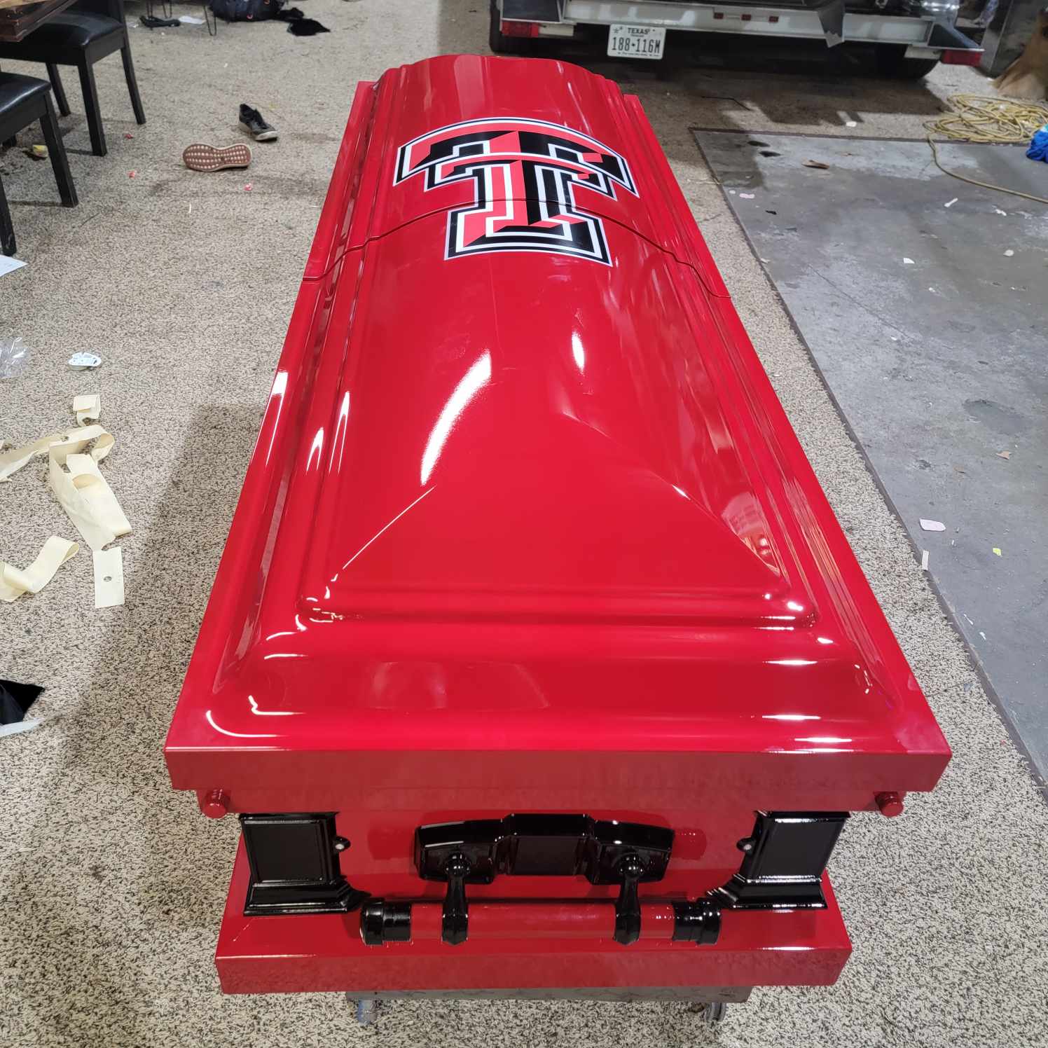 Head on view of a gloss red Texas Tech casket with black hardware sitting in the shop