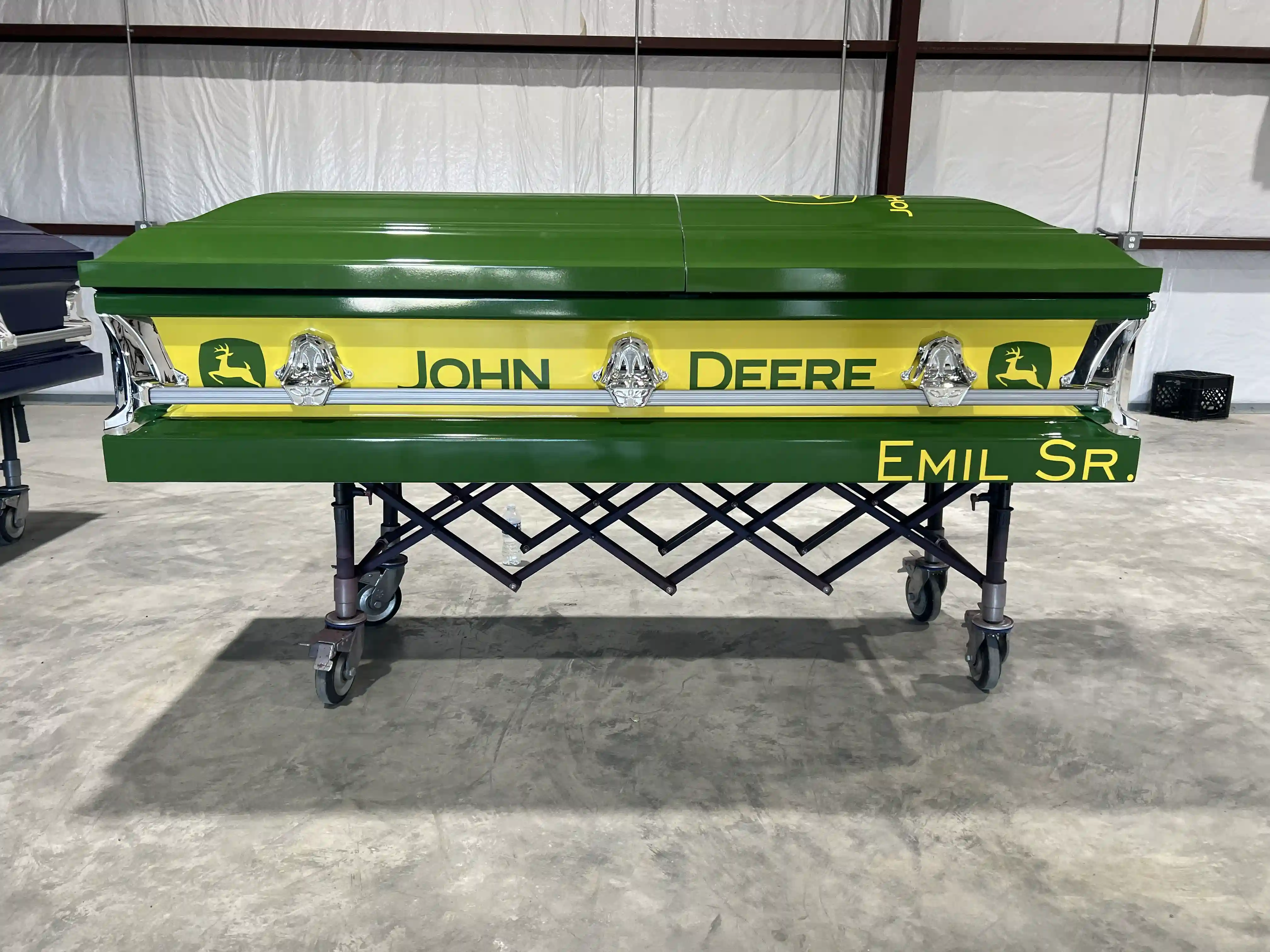 John Deere green casket with a yellow leaping deer band, chrome handles and EMIL SR. on the base