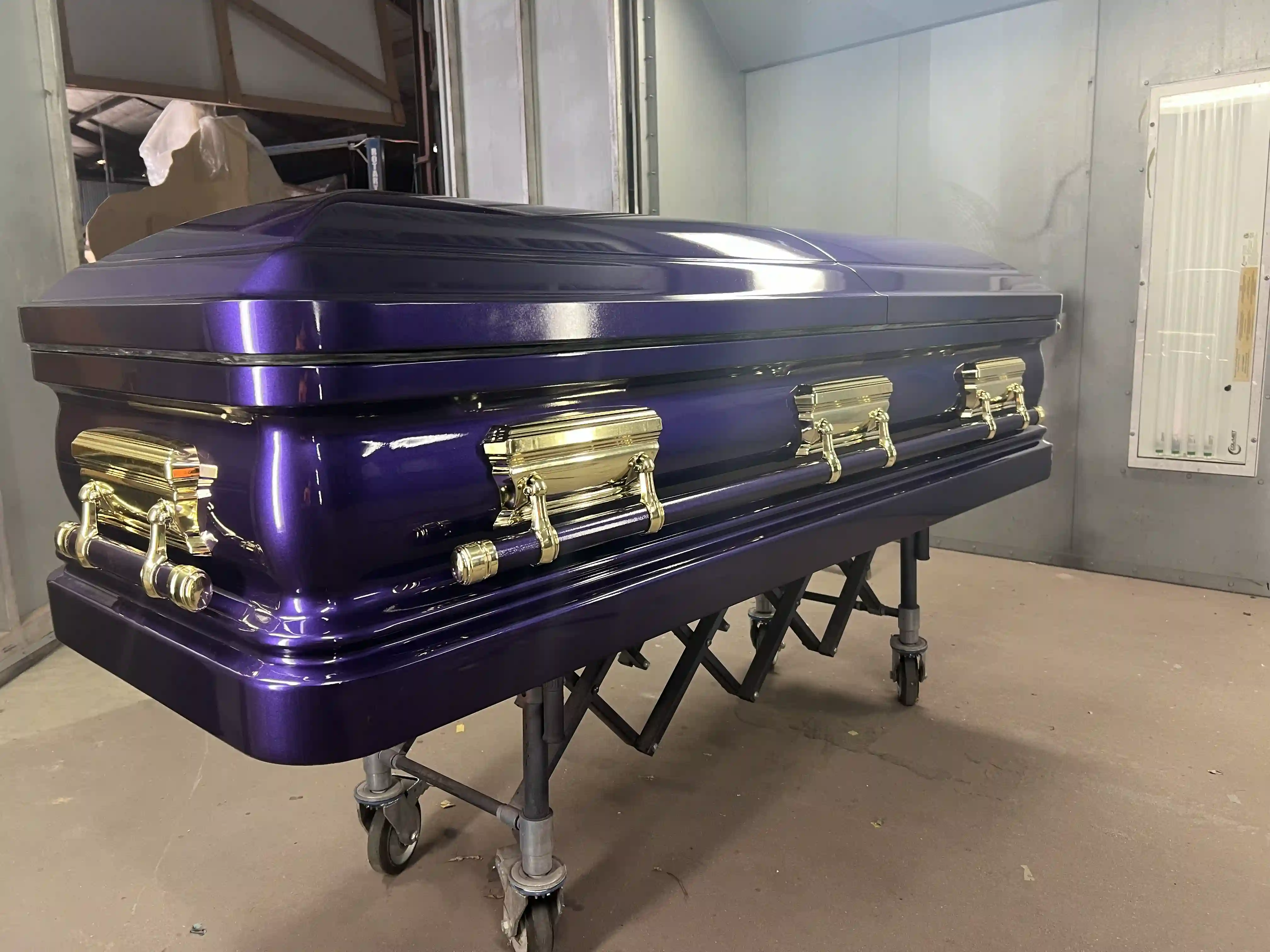 Violet pearl casket paired with bright gold hardware, photographed inside the spray booth