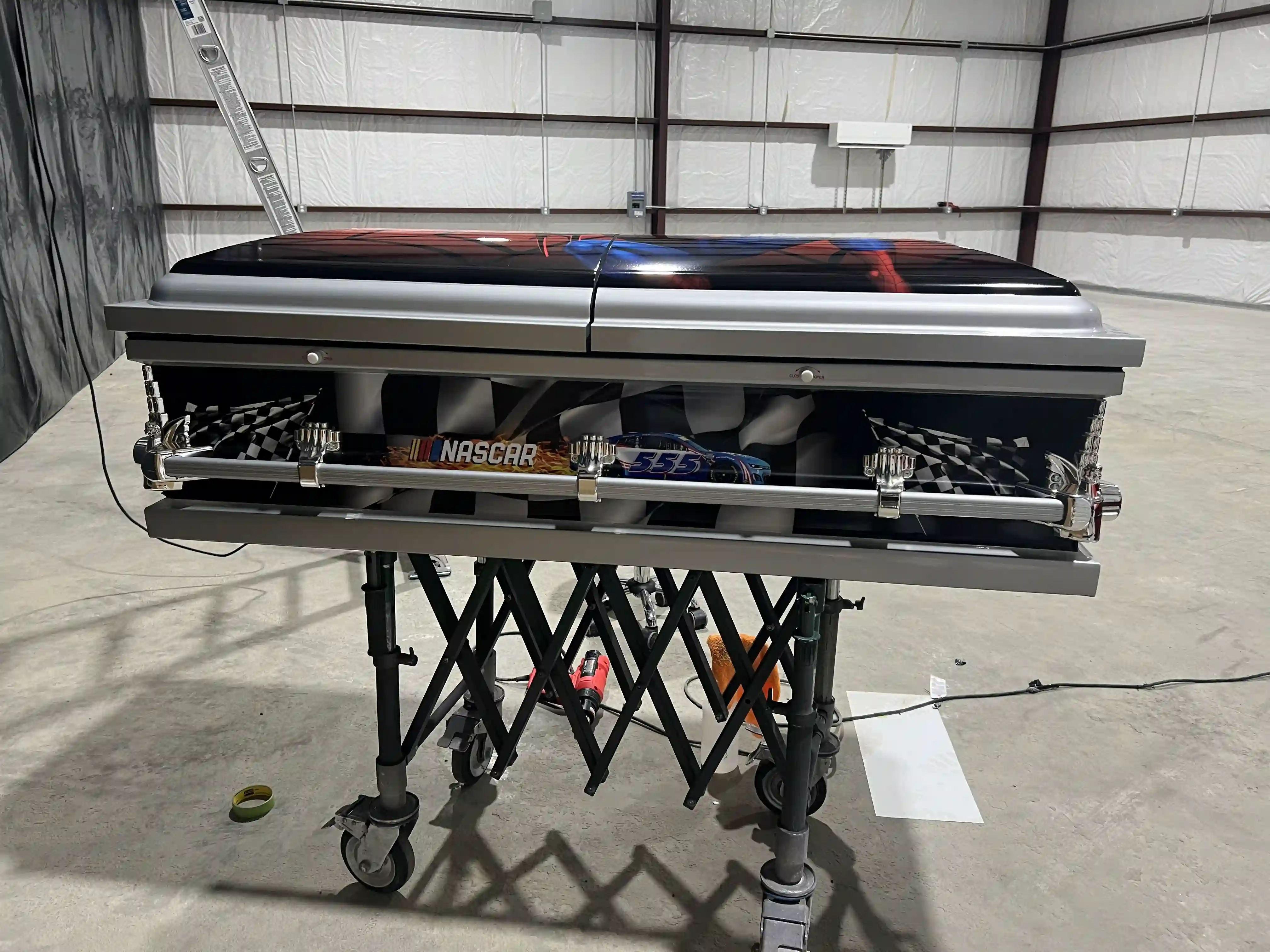 NASCAR checkered flag panels and chrome rails on a silver child casket with a Spider-Man lid