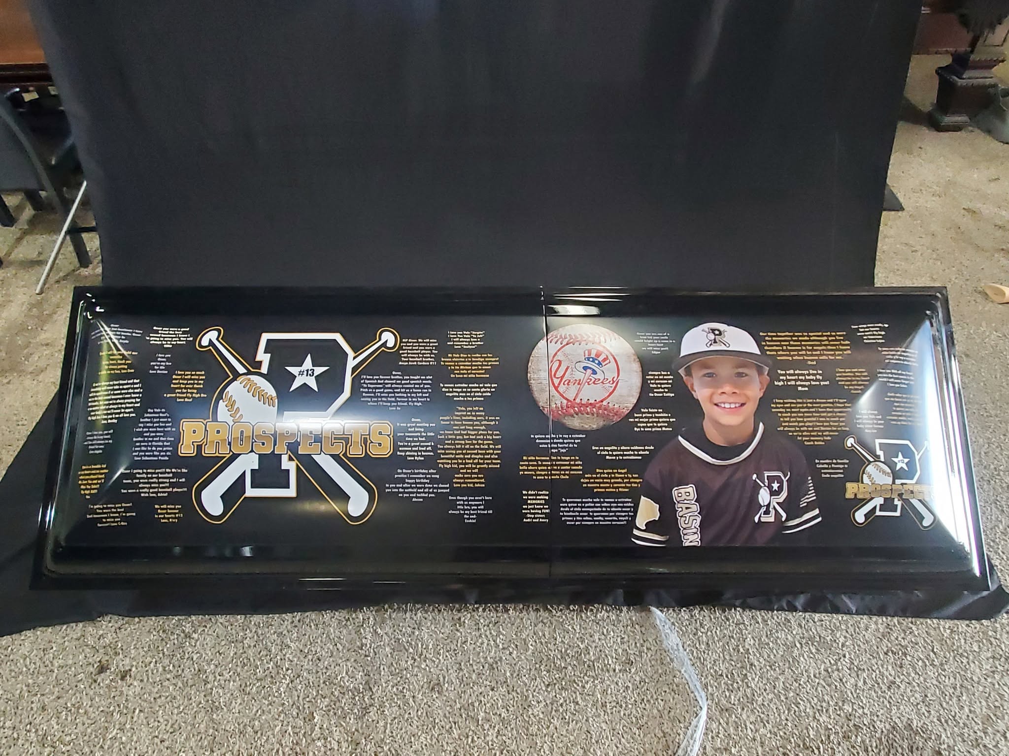 Black child casket wrapped with a Prospects baseball logo, a Yankees ball and a player portrait