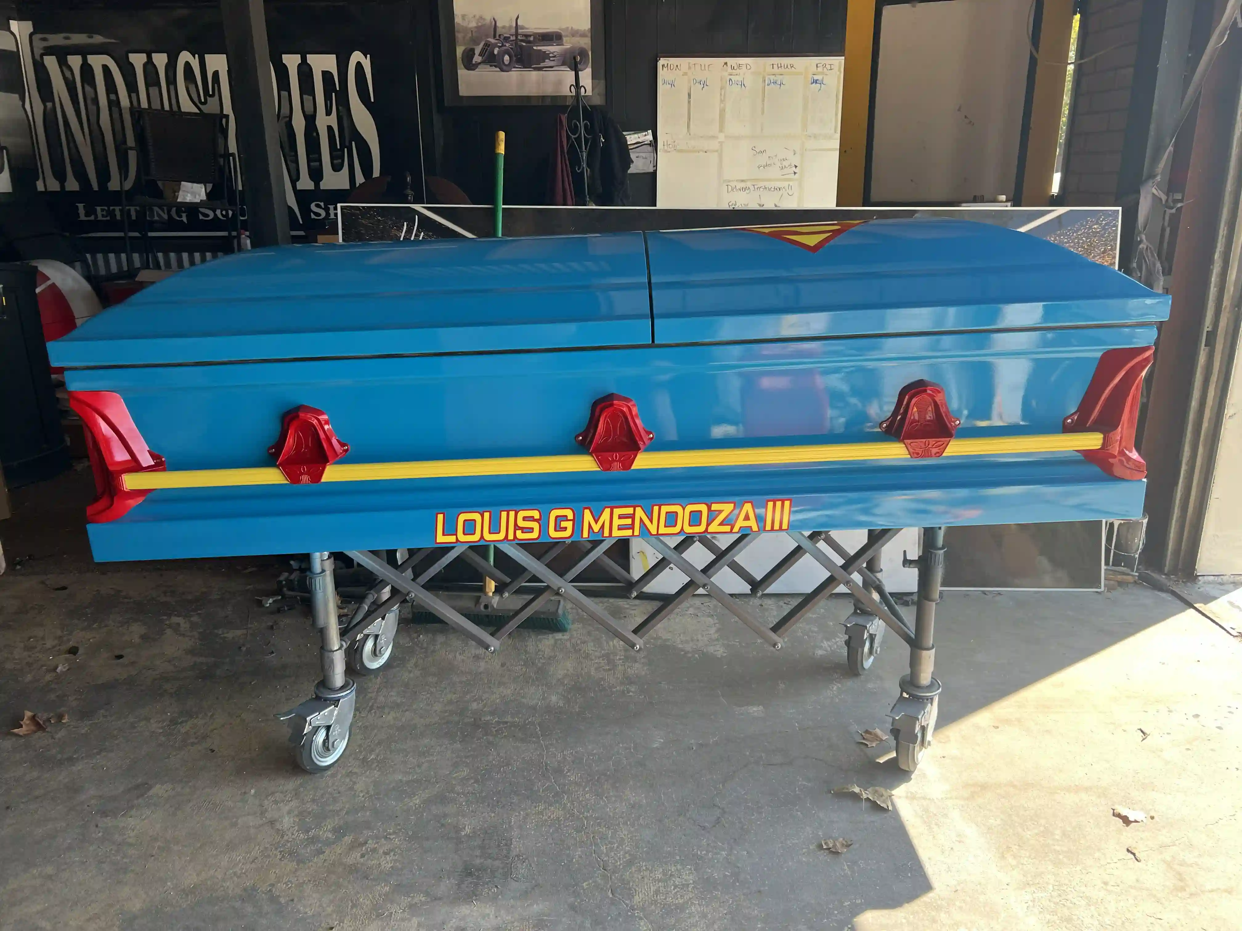 Blue Superman casket for Louis G Mendoza III with red handles and a yellow accent rail