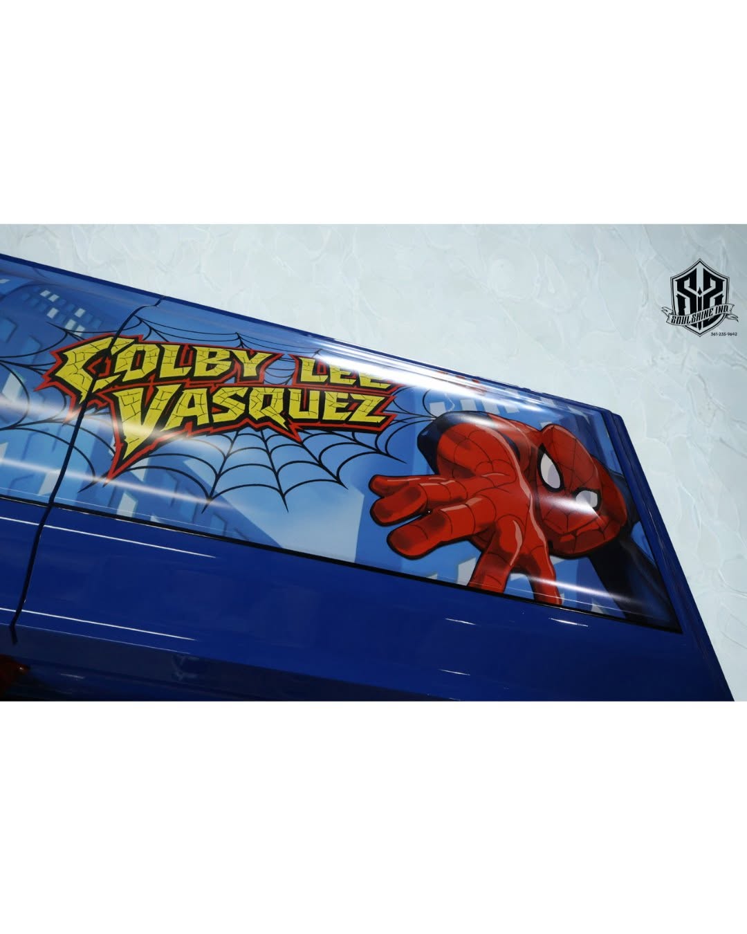 Close view of a blue Spider-Man child casket lettered Colby Lee Vasquez over a web skyline