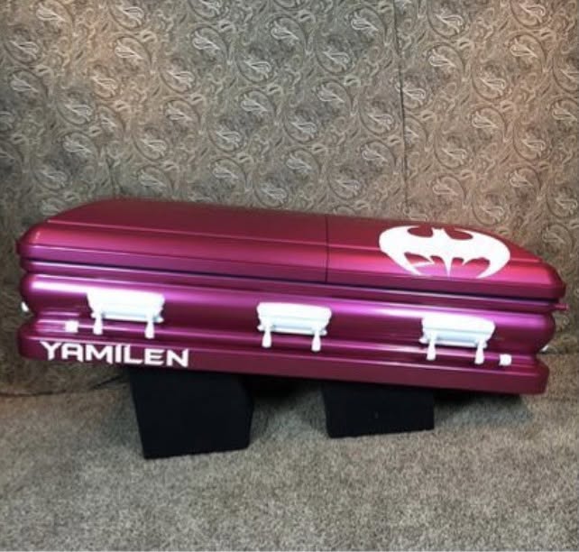 Metallic magenta child casket with a white Batman emblem and the name Yamilen on the base